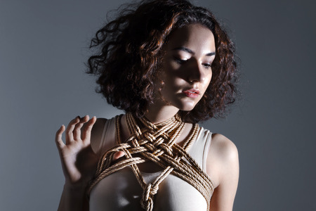 Sexy cute beautiful brunette female woman adult with curve hair wears beige bodysuit and rope...