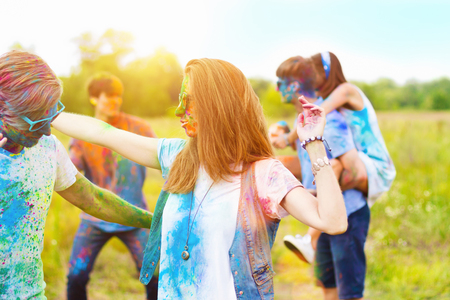 Happy holi party: sunny beautiful women females teenagers and males men in sunglasses celebrating happy holi festival in spring, summer day outdoor in green park with light leaks and colorful powderの写真素材