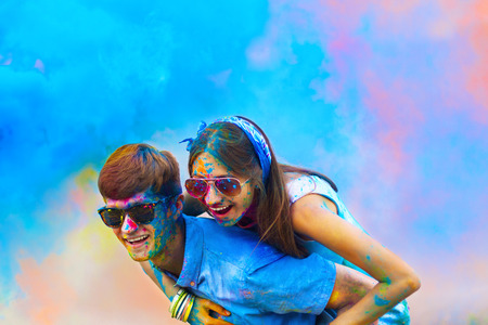 Happy holi party: sunny beautiful couple in love teenagers female male in sunglasses celebrating happy holi festival in spring, summer day outdoor in green park with light leaks and colorful powderの写真素材