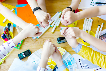 Top view of hands of business people holding hands of each other over desk in creative office....