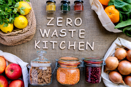 Reusable shopping bags with inscription in wooden letters on background of burlap. Alternative to disposable packages. Pouches with fruits and vegetables, glass jars with grains and spices. Zero wasteの写真素材