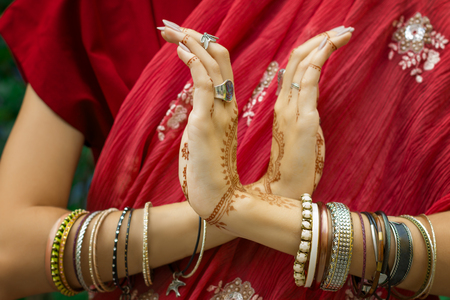 Beautiful woman in traditional Muslim Indian wedding pink red sari dress hands with henna tattoo jewelry and bracelets do hands nritta odissi Samyuta hastas dance. Movement nagabanda couple of snakesの写真素材
