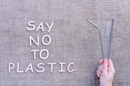 Metal reusable sustainable straws for cocktails and drinks isolated on brown craft fabric...