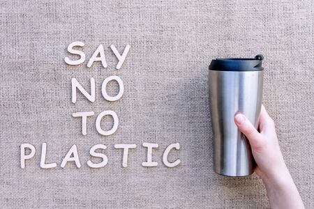 Reusable sustainable metal thermal coffee cup isolated on brown craft fabric background. Refuse, reduce, recycle and zero waste concept. Ecology, cut plastic footprint.の写真素材