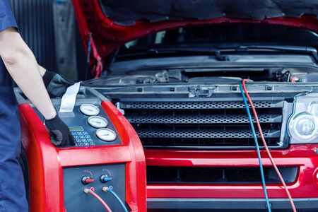 Mechanic is repairing car at service station. Repairer in jumpsuit is conducting diagnostics....