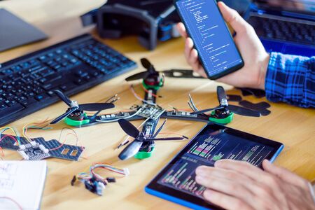 Closeup programmer hand are holding smartphone and tablet with program code of software on screen...