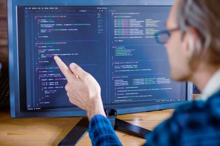 Man freelancer in glasses is writing software, working at home, office. Programmer developer is...