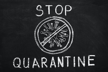 White chalk inscription stop quarantine on blackboard. Image of virus SARS-CoV-2, 2019-nCoV, covid -19, viral infection that leads to pneumonia, in prohibition circle. Coronavirus pandemic epidemic.の写真素材