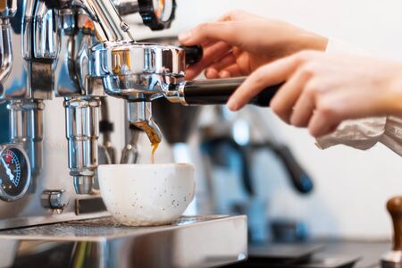 Closeup process of preparing, brewing latte, cappuccino, espresso, americano using professional metal steel coffee machine in kitchen of cafe, restaurant. Barista workplace. Hot drinks concept.の写真素材