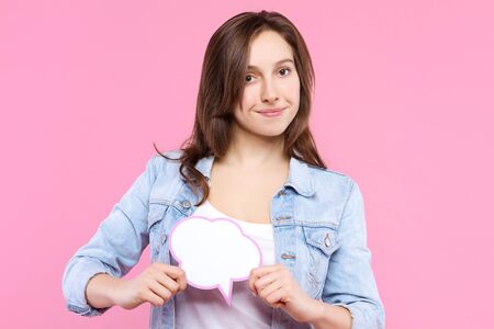 Pretty girl in white t-shirt, denim jacket is holding in hand paper decorative thinking, speaking...