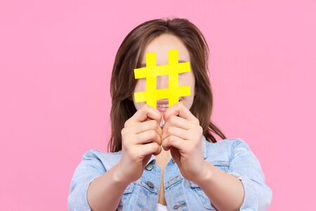 Pretty girl user of social media in white t-shirt, denim jacket is holding in hand yellow paper...