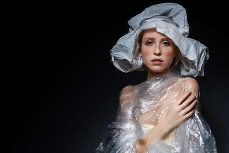 Portrait of unhappy upset girl with plastic bag on head. Young woman is choking, wrapped, bounded,...