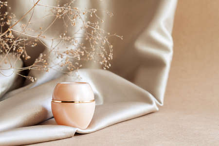 Closeup jar of moisturizing niche luxury face cream on background of beige fabric drapery. Cosmetics, products for care and personal hygiene concept. Minimalist packing, branding.の写真素材