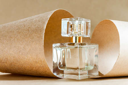 Closeup glass bottle of aromatic niche floral luxury perfume on abstract background of craft paper....