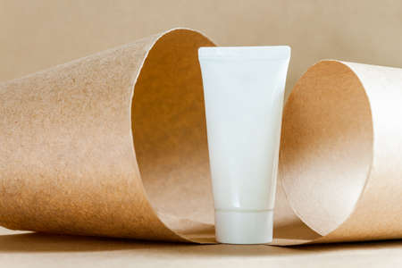 Closeup white tube of moisturizing niche luxury cream on abstract background of craft paper. Cosmetics products for care and personal hygiene concept. Minimalistic packing, branding.の写真素材