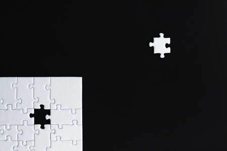 White puzzles are stacked on left bottom of black background. One piece located separately on social...