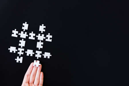 Hashtag icon laid out from white pieces of puzzles on black background. Number sign for reading social media messages, indicating start. Using, surfing, searching on internet, blogging concept.の写真素材