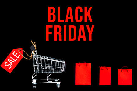 Little shopping cart with red paper bags on background canvas. Black friday sale, cyber monday...