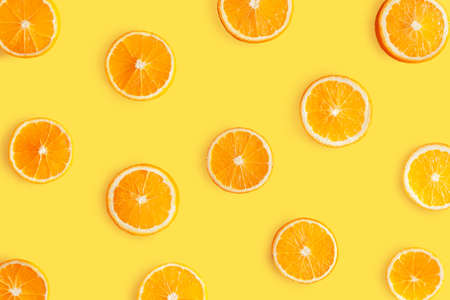 Top view of pattern, laid out slices of juicy oranges on yellow background. Summer tropical citrus...