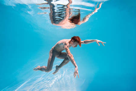 Male Caucasian man swimmer diver dancer swims under water in the sea. Summer tourism, travel journey trip voyage, holiday and vacation. Concertation, art, beauty and freedom conceptの写真素材