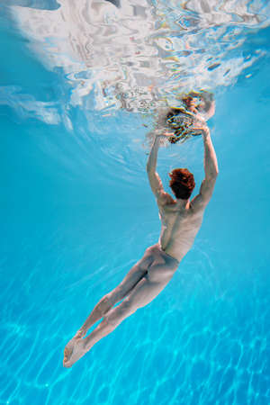 Male Caucasian man swimmer diver dancer swims under water in the sea. Summer tourism, travel journey trip voyage, holiday and vacation. Concertation, art, beauty and freedom conceptの写真素材