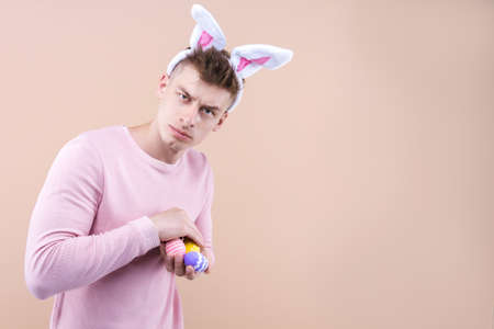 Young handsome concentrated male wearing traditional bunny rabbit ears is standing over isolated...