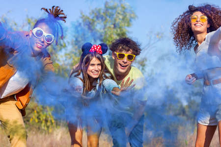 Beautiful young man and woman hold light up colored smoke bombs - Happy friends having fun in the...