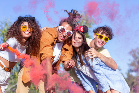 Beautiful young man and woman hold light up colored smoke bombs - Happy friends having fun in the...