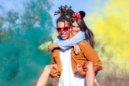 Beautiful young man and woman in light up colored smoke bombs - Happy friends having fun in the park...
