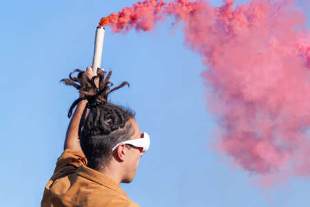 Beautiful young man hold light up colored smoke bombs - Happy friends having fun in the park with...