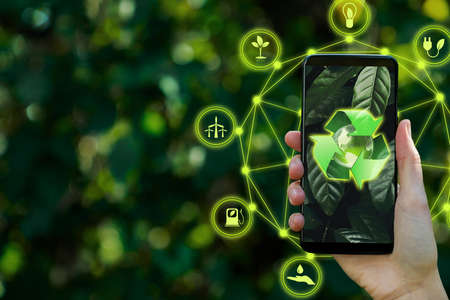 Female hand is using smartphone with environment icons over network connection. Concept saving energy in nature, growth and success. Ecology conservation by technology. Earth day. Save planet.の写真素材