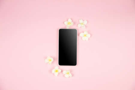 Mobile phone with black screen on neutral pastel pink background with empty space for text inscription. Smartphone for wireless communication, work, business and leisure. Social media likes concept.の写真素材