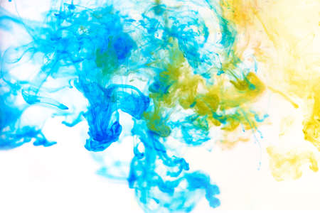 Bright blue and yellow acrylic paint swirling in water. Ink moving in liquid creating abstract...