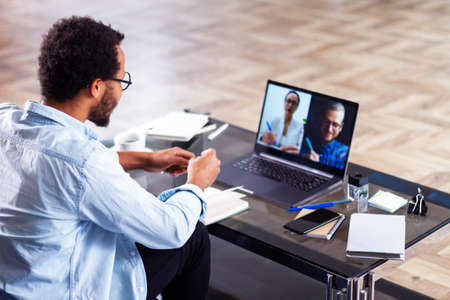 An African-American businessman using computer app for communication with diverse team on the...
