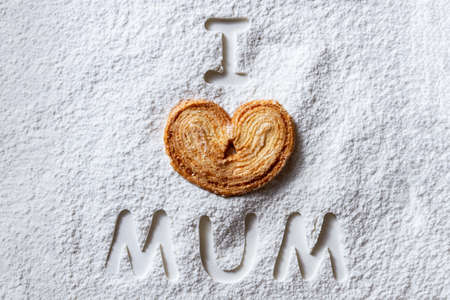 Sweet ginger cookies hearts with sugar and words I love mum on a white flour background. Happy...