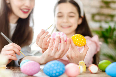 Happy Easter atmosphere! Funny, pretty, creative mom teaching, explain, to her cute, small, joyful...