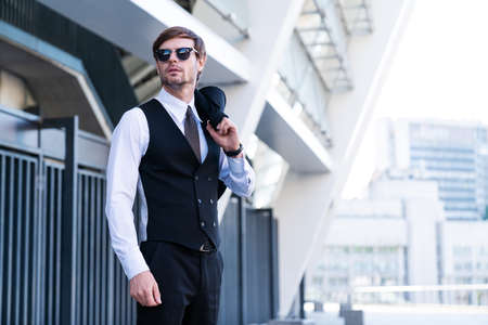 Portrait of a young and handsome successful male trader businessman wearing suit, sungluss. Stylish...