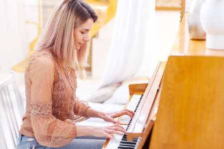 The piano teacher experienced pianist preparing to lesson. Creative hobby and activity. Beautiful woman composer write romantic song, playing piano. Musical artist create instrumental acoustic melody.の写真素材