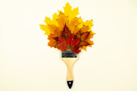 Paint brush made from yellow and brown collection of fallen leaves different shapes and colors. Autumn poster with brush bouquet from colorful leaves. Seasonal elements isolated on white background.の写真素材