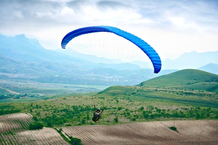 Paraglider soaring over the mountainsの写真素材