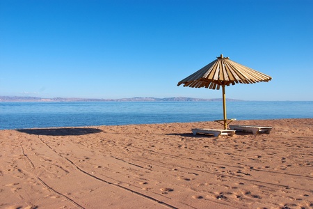 Wooden umbrella and chairs on the beachの写真素材