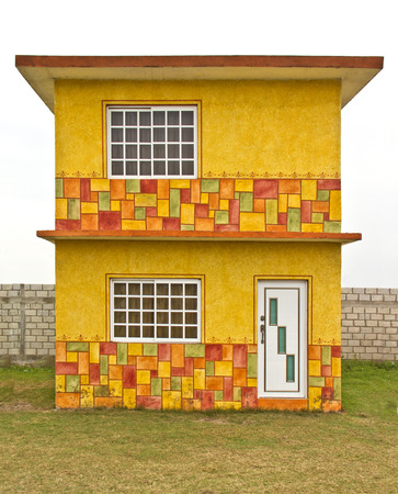 small yellow house surrounded green lawnのeditorial素材