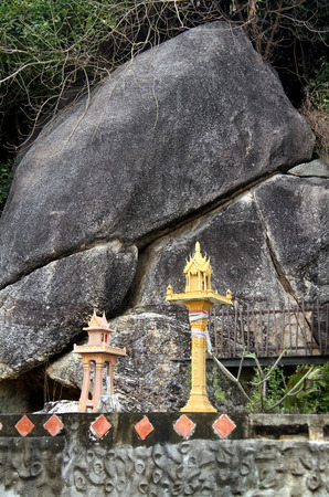spirit house opposite the rock in thailandの写真素材