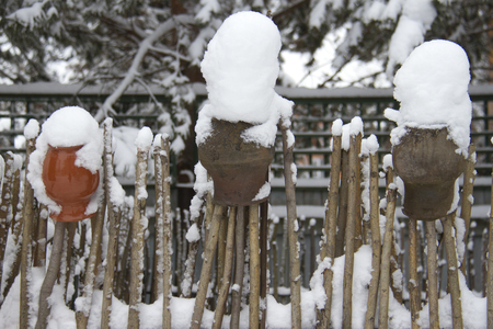 old wooden fence and ceramic jars covered with snowの写真素材