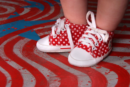 baby feet wearing red sport shoesの写真素材