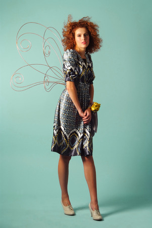 romantic red haired girl poses with a butterfly wingsの写真素材