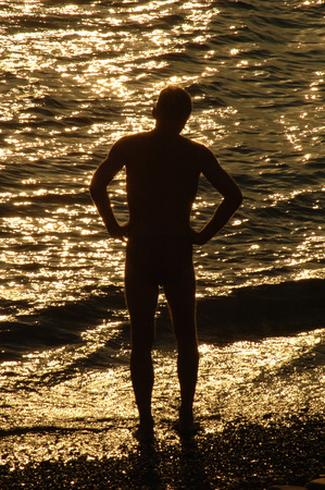 silouette of a man in front of brightly lighted seaの写真素材