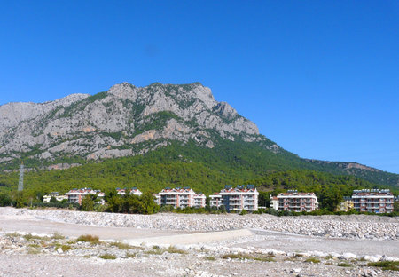 Multi-storey houses at the foot of a mountain near a parched riverの写真素材