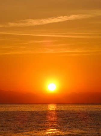 Sunrise from behind the Mediterranean Sea against the backdrop of the mountainsの写真素材