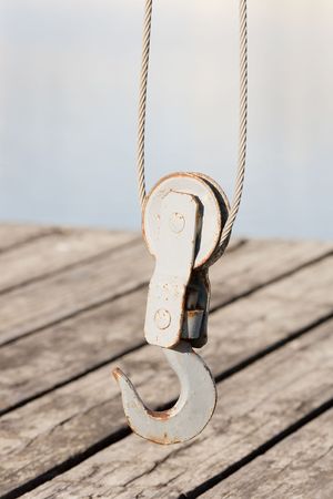 Closeup photo of a hook of a small mechanical crane on the dock.の写真素材